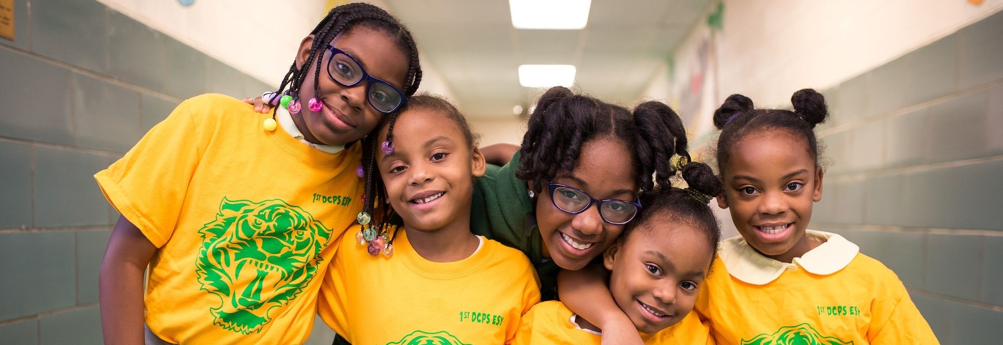 Four young students and a teacher smiling